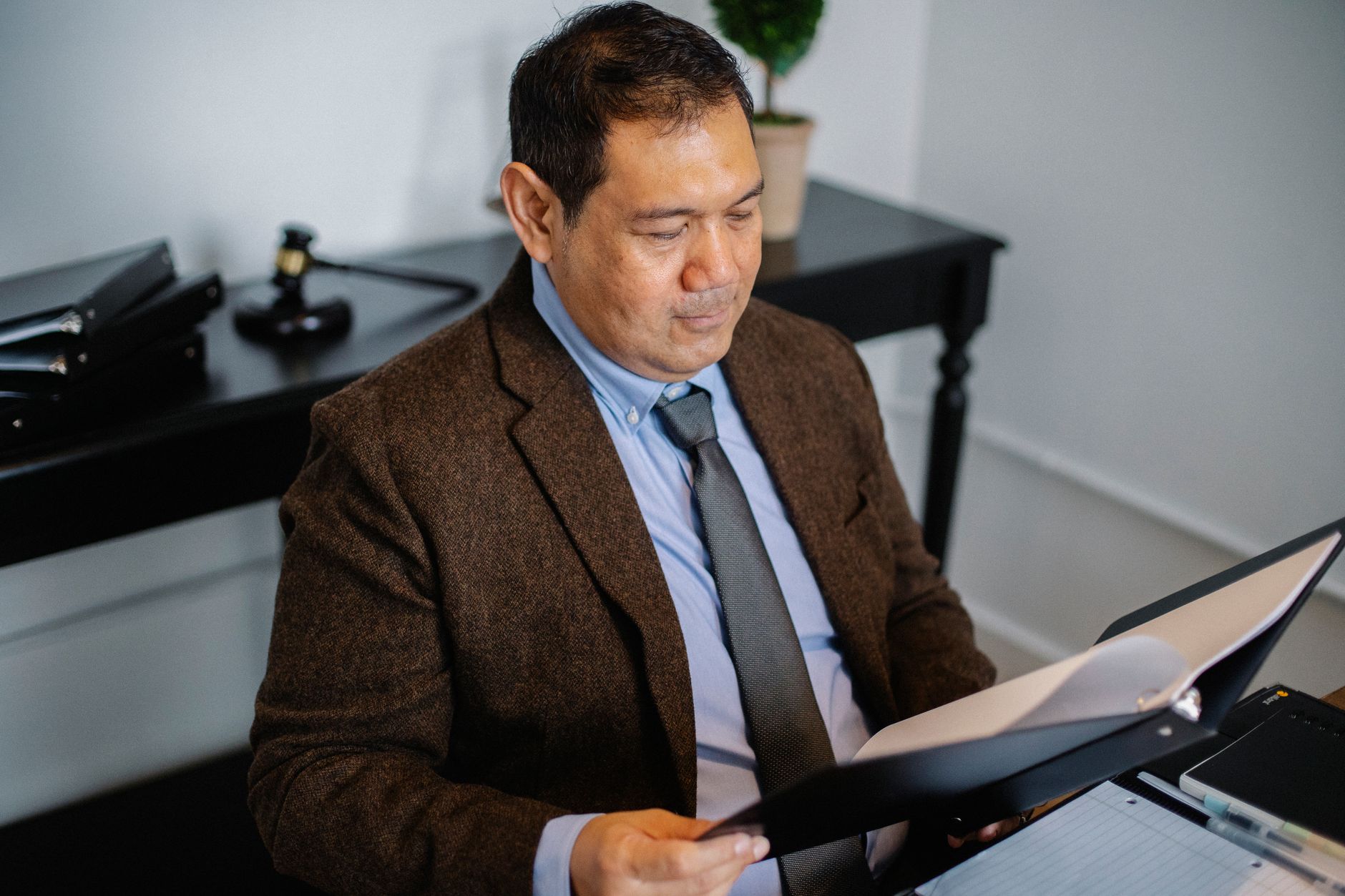 From above of serious ethnic lawyer in elegant suit checking report in folder on blurred background of office — illustrating: How to Choose a Green IT Consultant in Central Florida Without Overpaying for Compliance